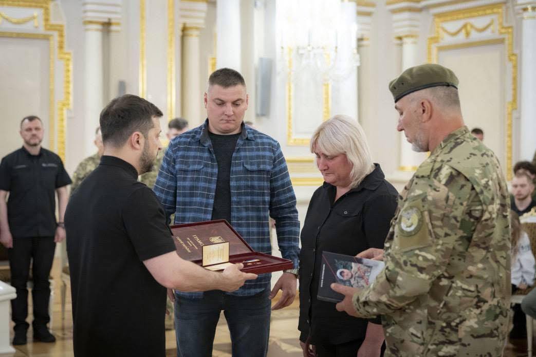 Президент України Володимир Зеленський передає нагороду родині захисника