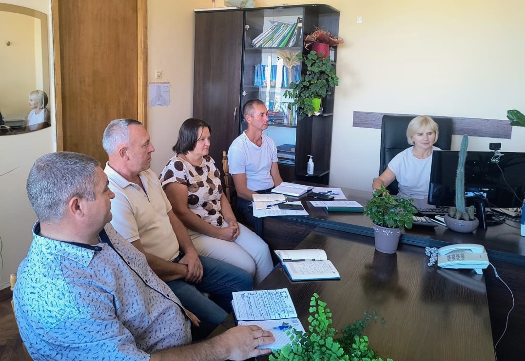 В кабінеті за робочим  столом сидят працівники, перед ними монітор комп'ютера та записники