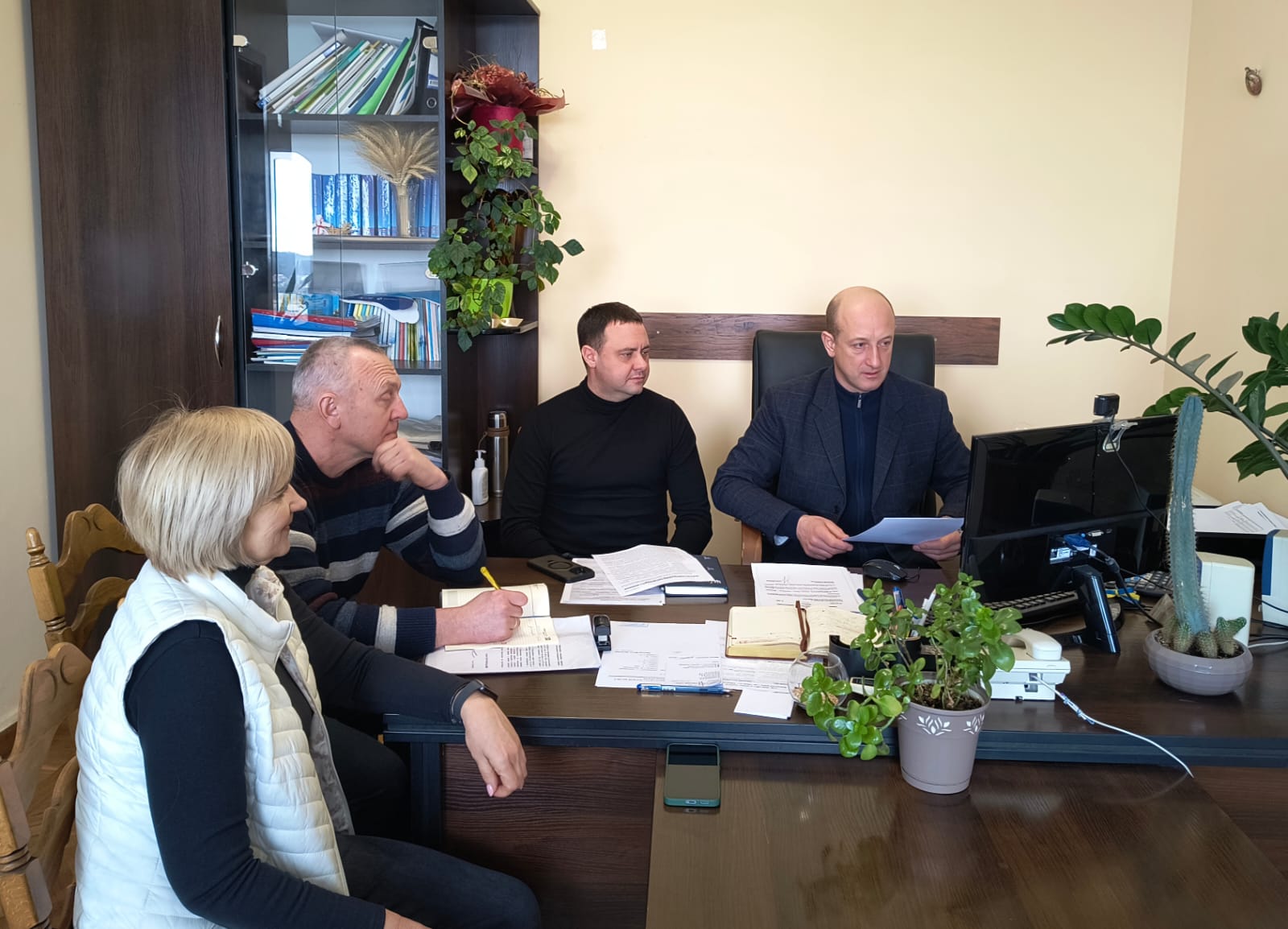 Учасники наради сидят в кабінеті за робочим столом перед ними монітор комп'ютера