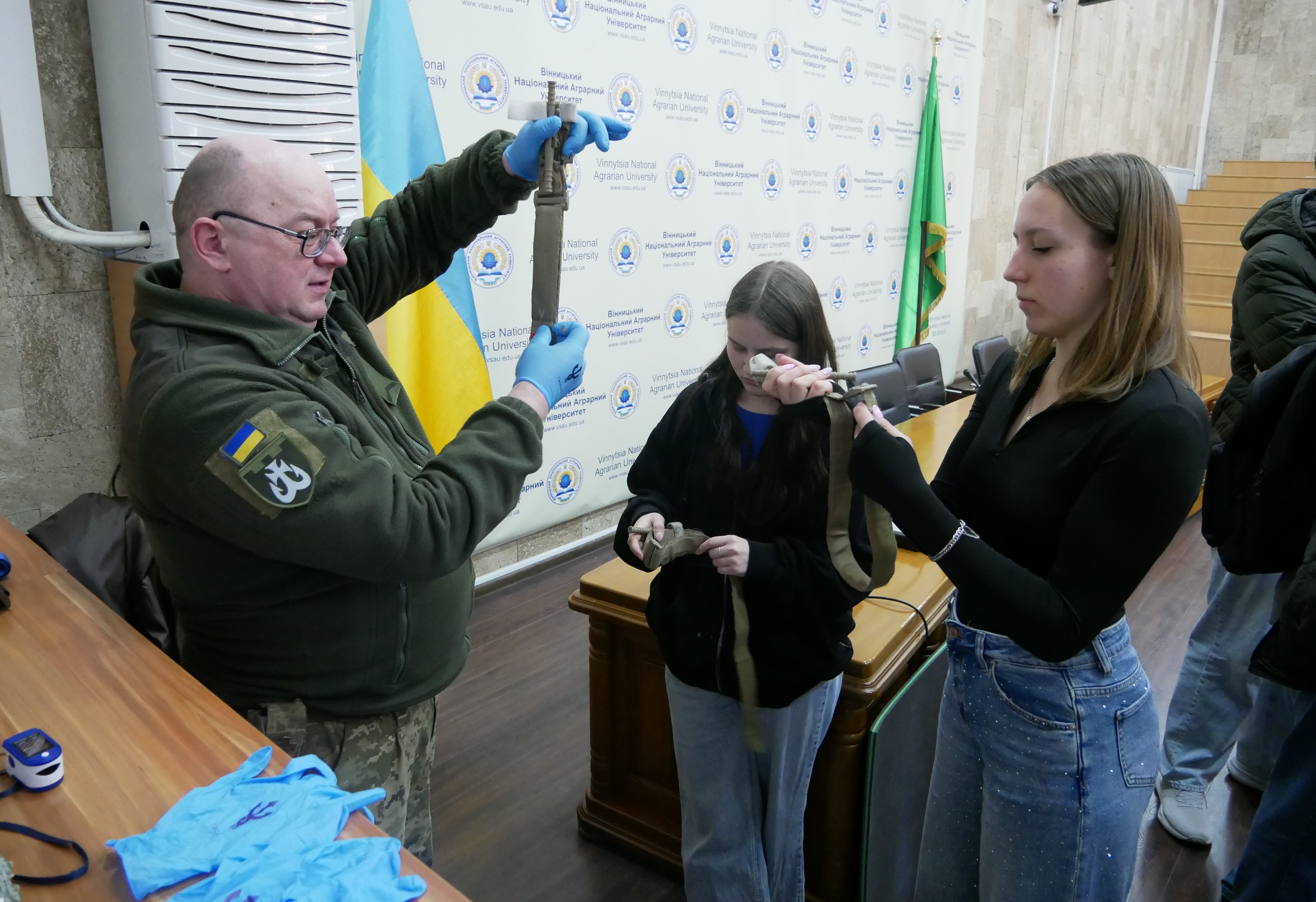 Чоловік-інструктор тримає у руках турнікет і щось розповідає.