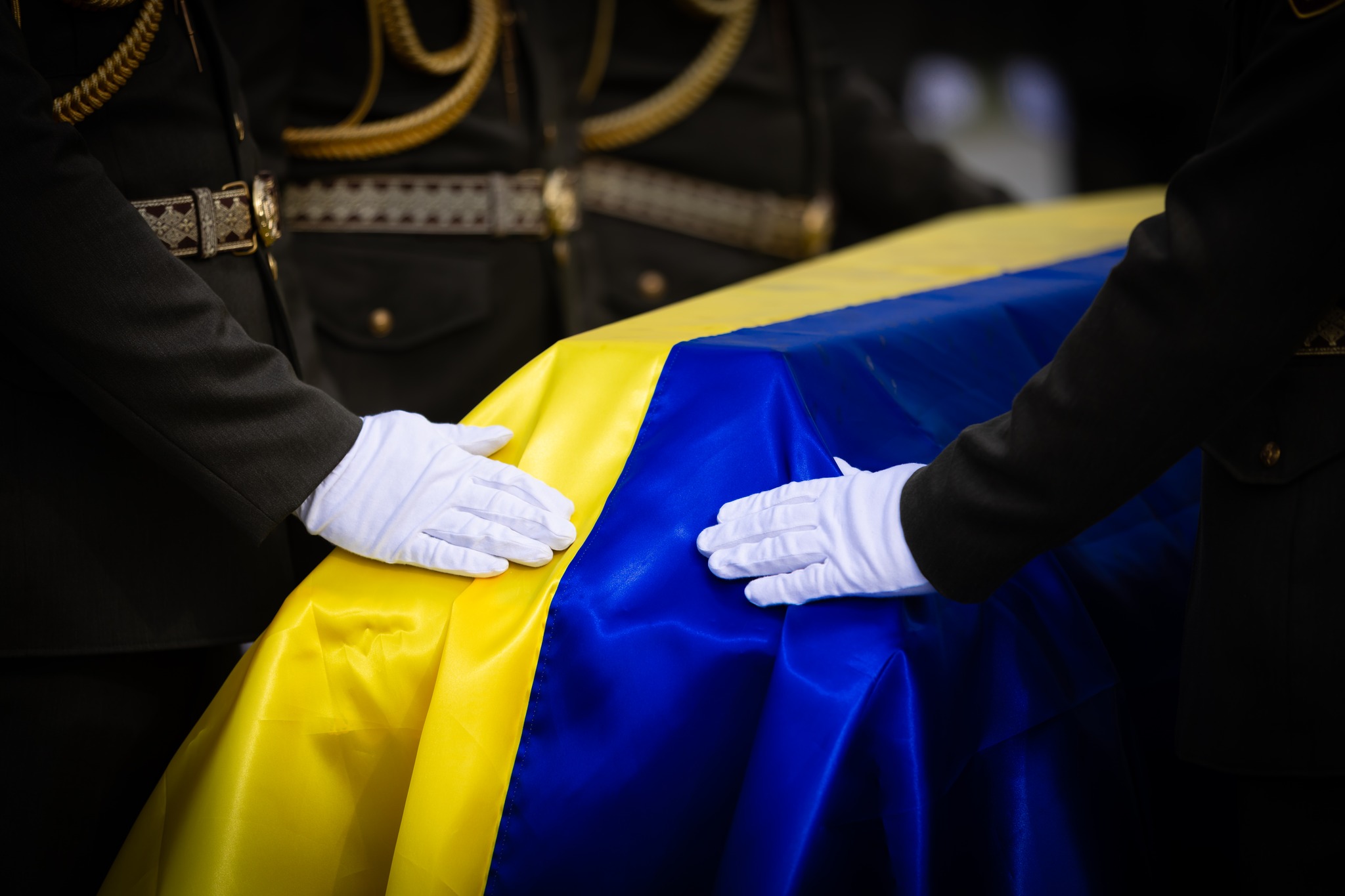 Військові тримають руку на труні, накриті прапором з тілом невідомого захисника