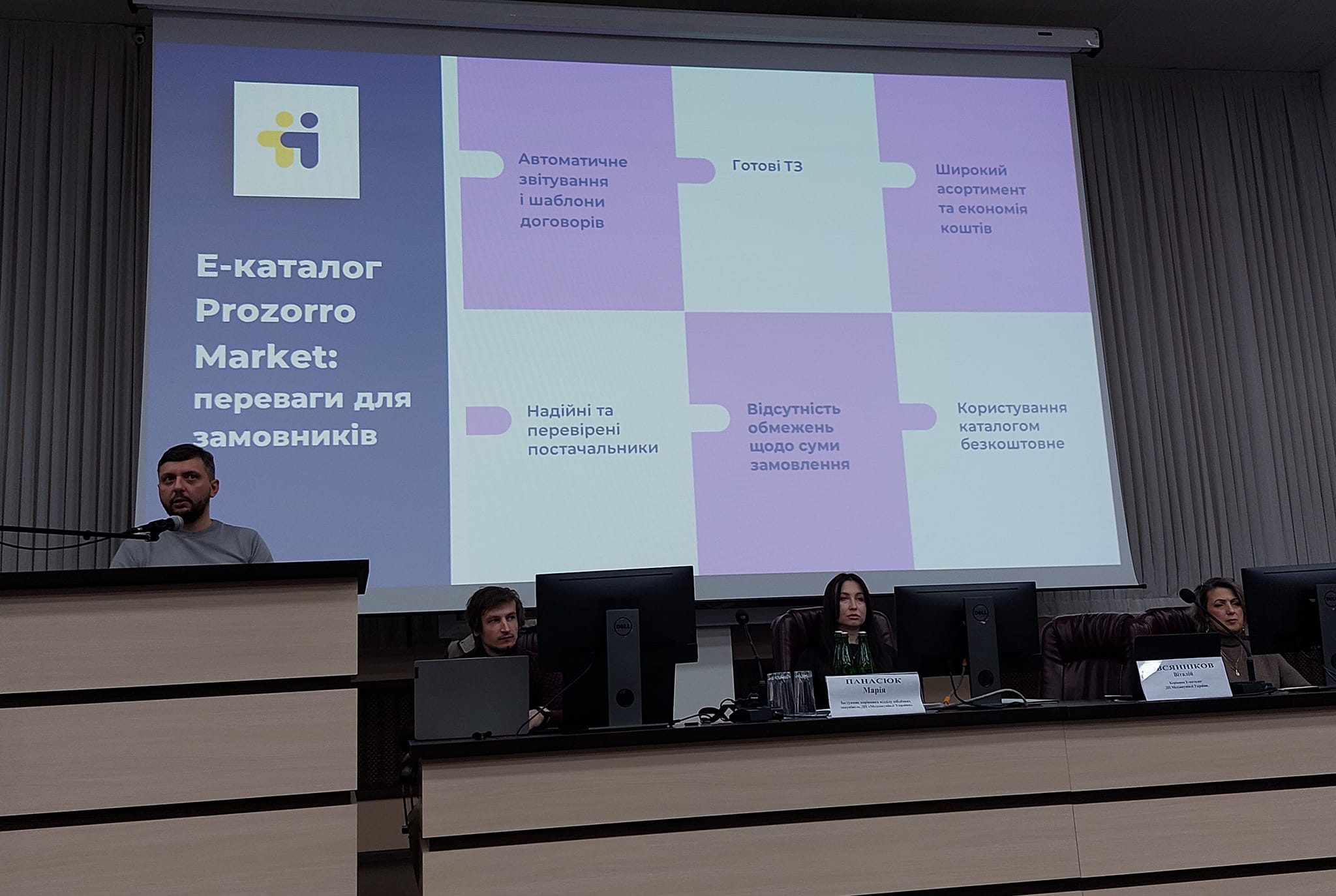 Чоловік стоїть за пультом з мікрофоном перед собою.
