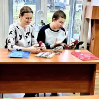 Двоє людей сидять за столом у класі і тримають ляльки-мотанки