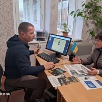 Люди сидять за робочим столом. Ознайомлюються з інформаційними матеріалами