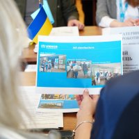 Учасники зустрічі розглядають фотоколаж про діяльність УВКБ ООН