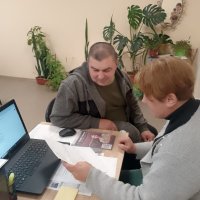 Люди сидять за робочим столом. Ознайомлюються з інформаційними матеріалами