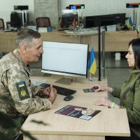 Люди сидять за робочим столом. Ознайомлюються з інформаційними матеріалами