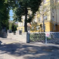 Вхід до жовтої будівлі. Сірий паркан