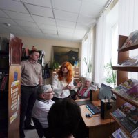 Люди обговорюють щось у залі бібліотеки біля столу з комп'ютером