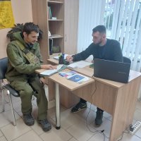 Люди сидять за робочим столом. Ознайомлюються з інформаційними матеріалами