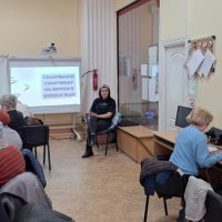 Люди працюють за комп'ютерами, встановленими на столах у навчальному класі і слухать викладача