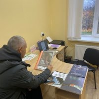 Чоловік сидить за робочим столом. Ознайомлюється з інформаційними матеріалами