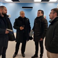 Чотири чоловіки стоять у кімнаті й розмовляють один з одним