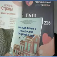 Жінка демонструє книгу, присвячену питанням протидії булінгу.