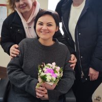 Троє молодих дівчат фотографуються. Одна з дівчат тримає в руках букет квітів