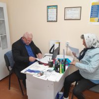 Люди сидять за робочим столом. Ознайомлюються з інформаційними матеріалами