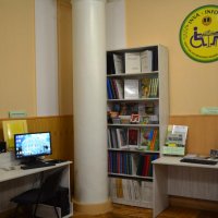 Зала бібліотеки з двома столами з комп'ютерами. Книжкові полиці