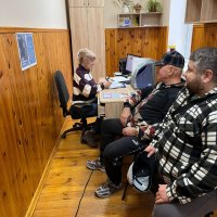 Люди сидять за робочим столом. Ознайомлюються з інформаційними матеріалами